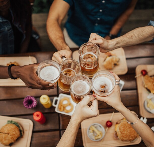 group of friends cheersing beer with burgers