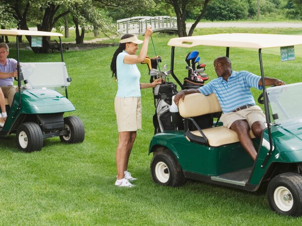two couple golfers on course riding in golf carts