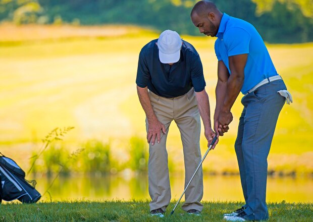 Golf Pro Teaching Male Golfer by pond