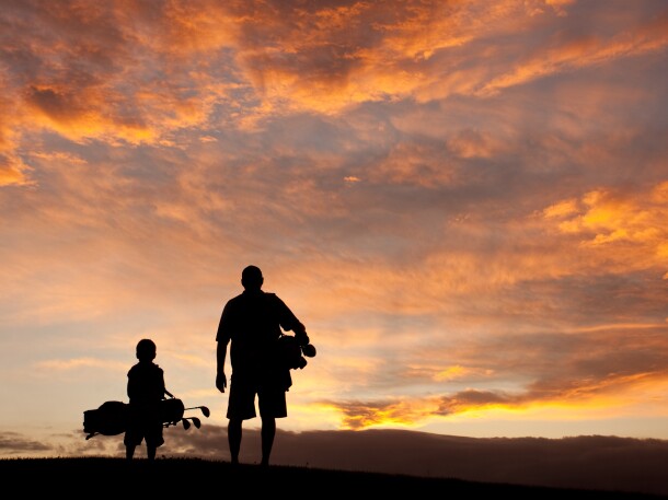 father and son on golf course at sunrise