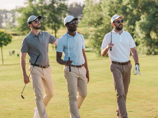 threesome group of male golfers walking on golf course