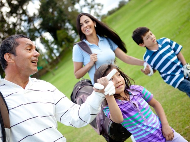 Family golfing - father mother daughter and son on the golf course