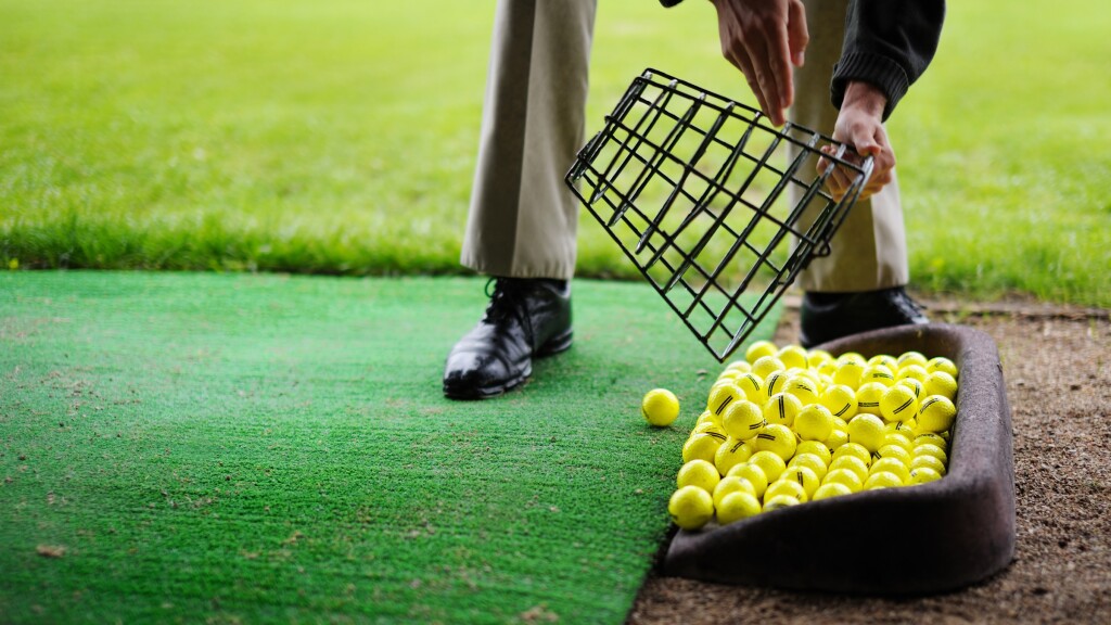range balls pouring out of basket at golf practice facility