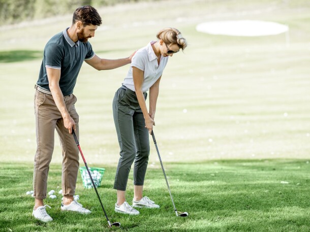 Woman with male instructor playing golf