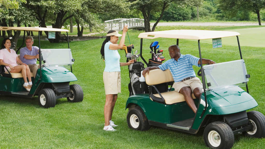 two couple golfers on course riding in golf carts