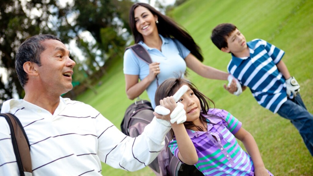 Family golfing - father mother daughter and son on the golf course
