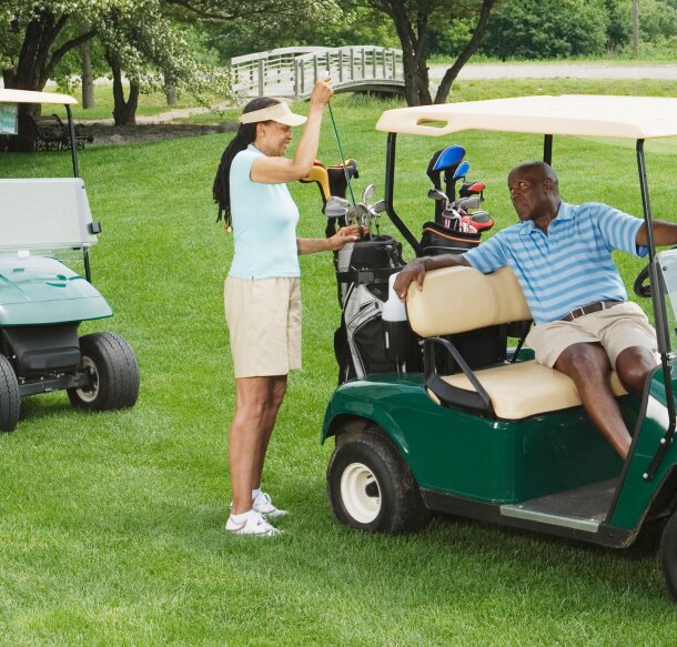 two couple golfers on course riding in golf carts