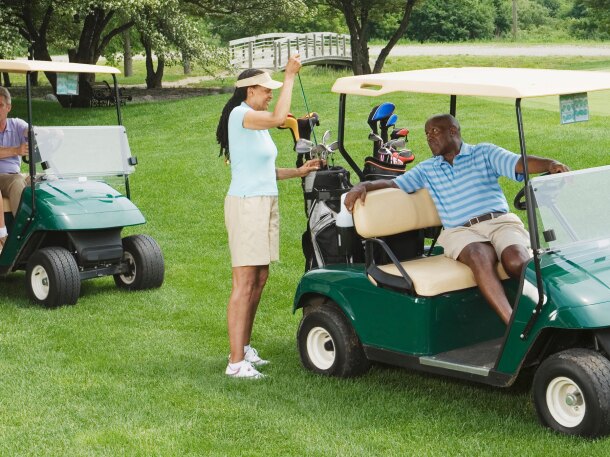 two couple golfers on course riding in golf carts