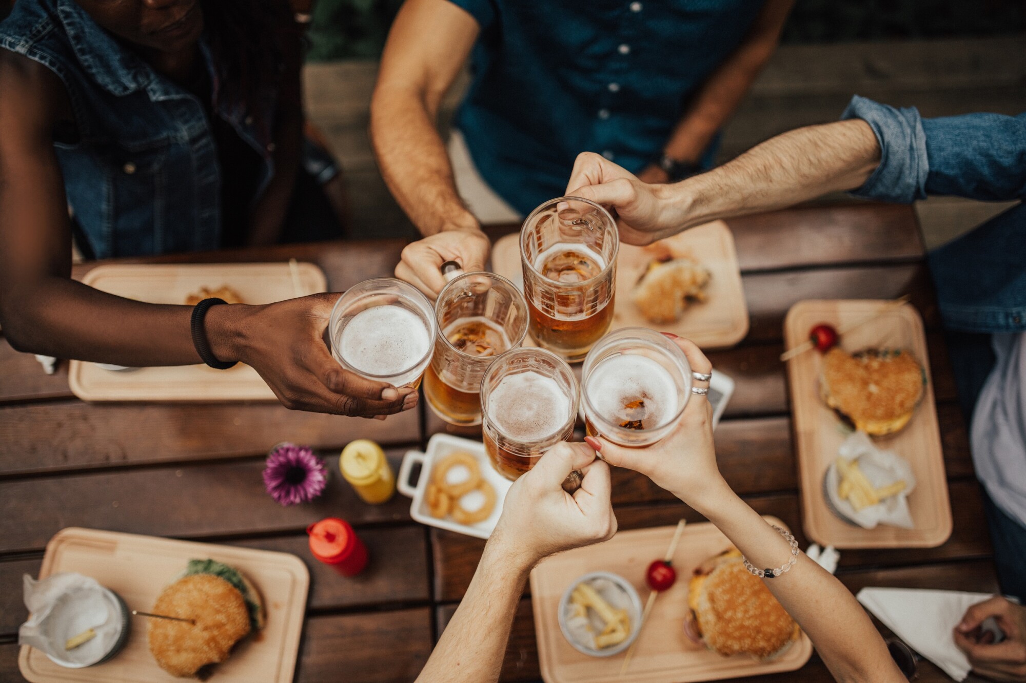 group of friends cheersing beer with burgers