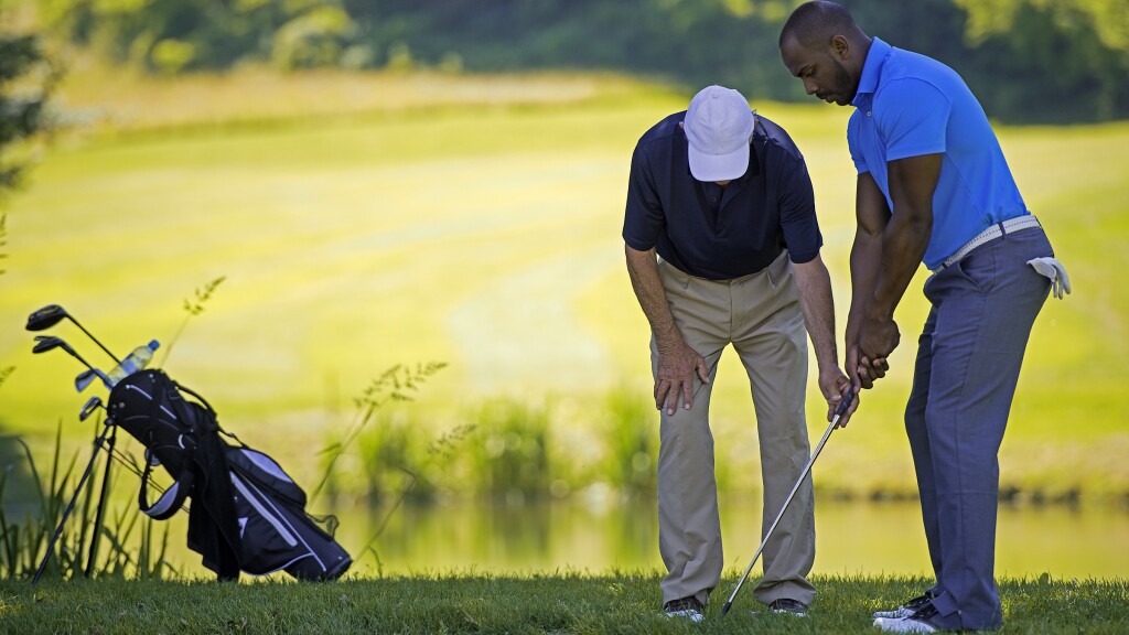 Golf Pro Teaching Male Golfer by pond