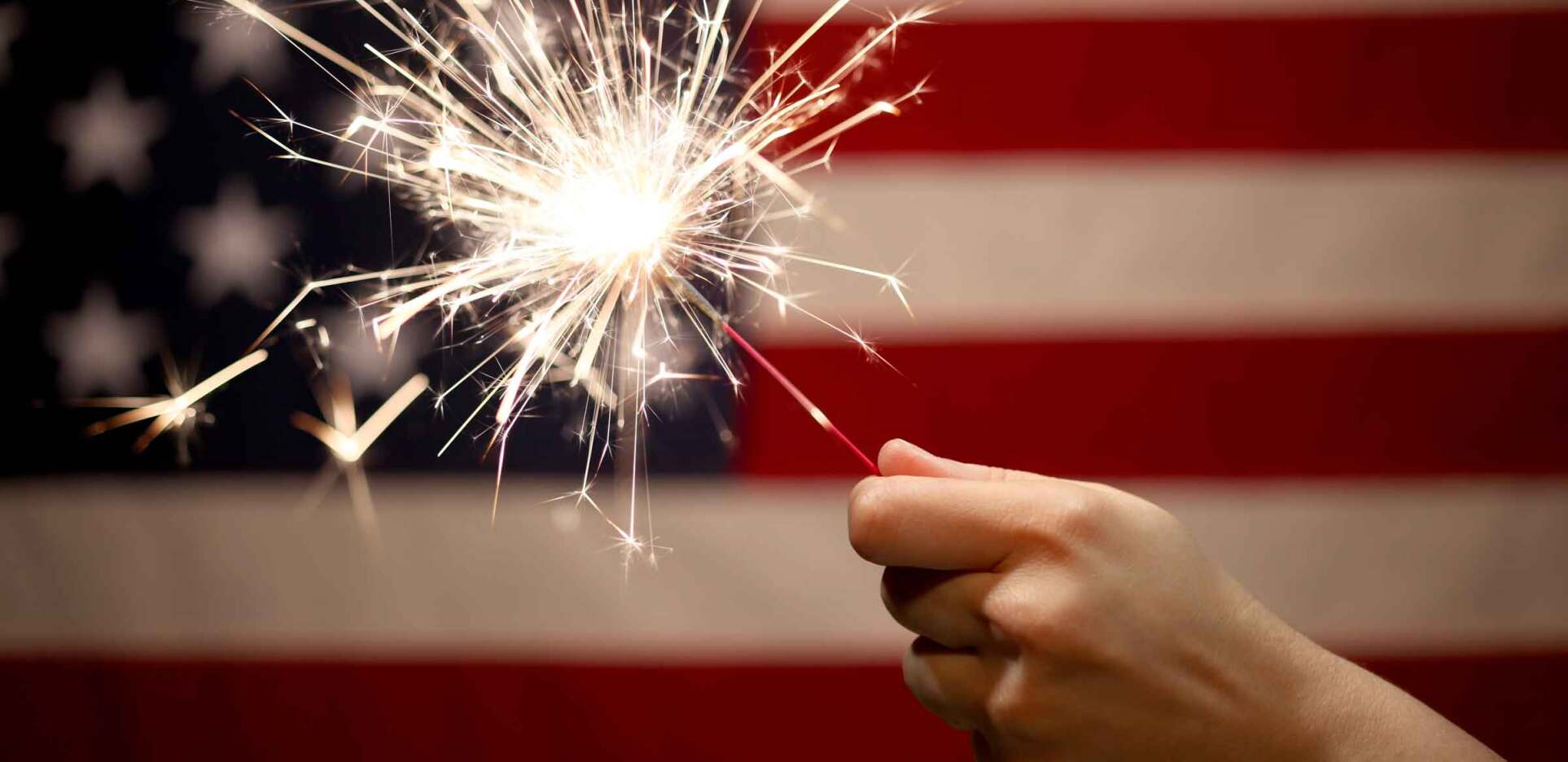 Sparkler in front of American flag celebrating the 4th of July