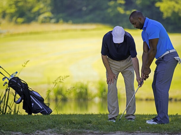 Golf Pro Teaching Male Golfer by pond