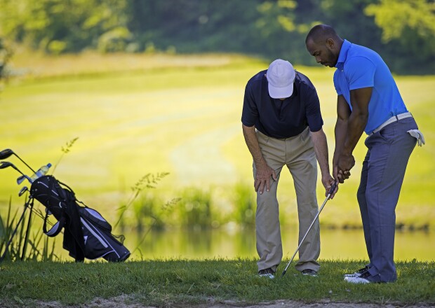 Golf Pro Teaching Male Golfer by pond