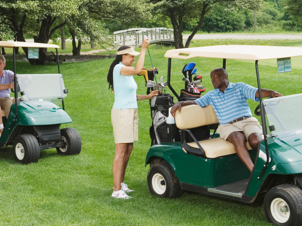 two couple golfers on course riding in golf carts