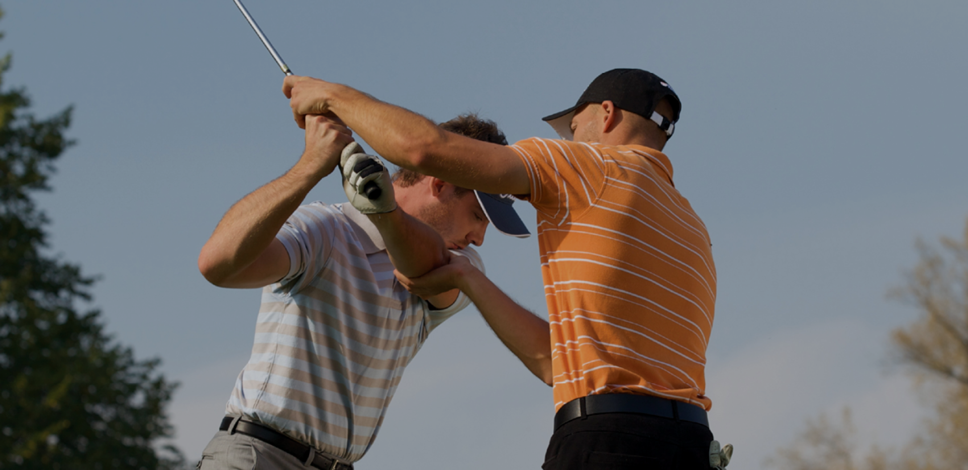 Man instructing another man in golf lessons