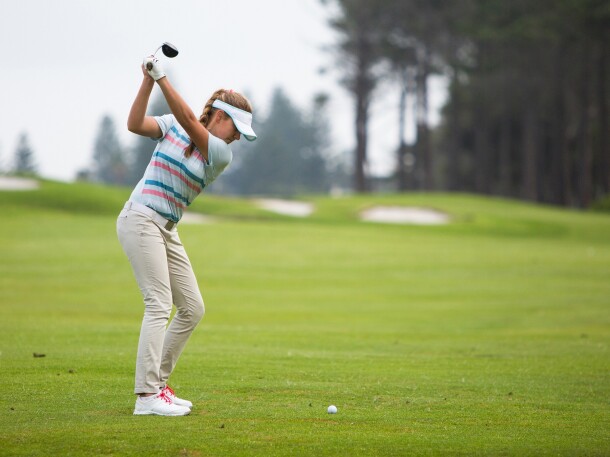 female golfer swinging club on golf course