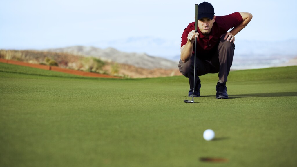 Single Male Golfer lines up his eagle putt.