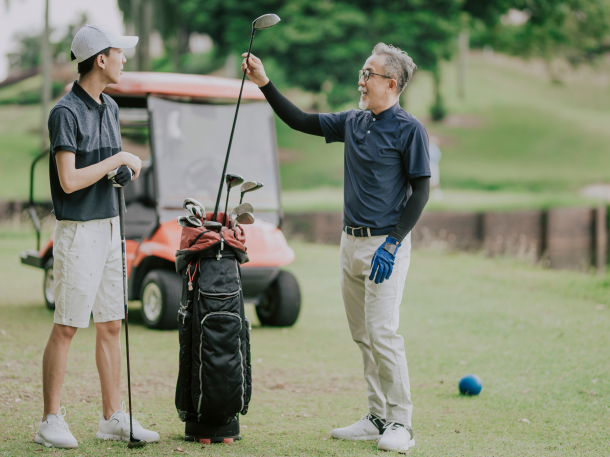 father son discussing golf game and choosing golf clubs at tee