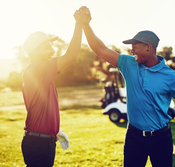 twosome golfers celebrate with high five on golf course with sunshine